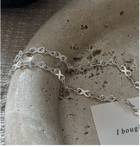Macro shot of silver S925 infinity link chain on textured stone jewelry display