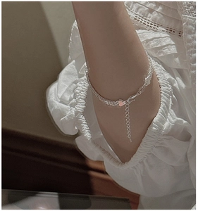 Détail d'un bracelet en argent S999 avec breloques cœur porté sur un poignet féminin