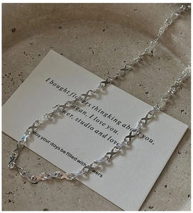 Close-up of S925 sterling silver necklace with interlocking X-shaped links on tray