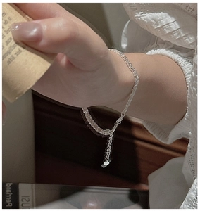 Détail macro du bracelet tressé en argent sterling S999 avec breloque cœur sur le poignet