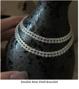 Macro detail of silver double-row shell bracelet on elegant black ceramic texture