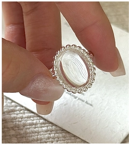 Detailed close-up of S925 sterling silver ring with oval white crystal and milgrain edge