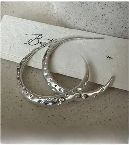 Macro detail of S925 sterling silver hoop earrings with a unique hammered metal texture