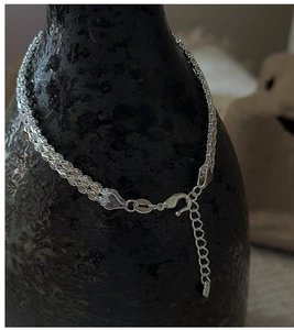 Close-up of S999 sterling silver woven chain bracelet with lobster clasp and heart charm