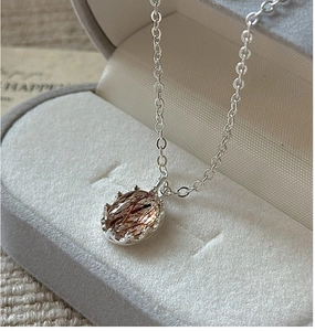 Macro shot of S925 silver necklace featuring a rutilated quartz pendant on jewelry box