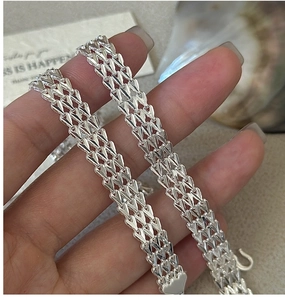 Detailed close-up of triple-strand V-shaped silver chain links with heart-shaped clasp