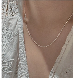 Detail view of S925 sterling silver twisted chain necklace on a model neckline