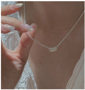 Close-up of S925 sterling silver cylinder pendant necklace worn on a lace background