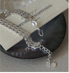 Macro shot of silver S925 sterling silver woven bracelet with heart pendant charm