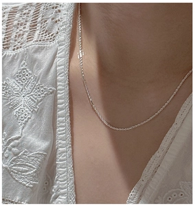 Detailed view of an S925 silver twist chain necklace on a model wearing white lace