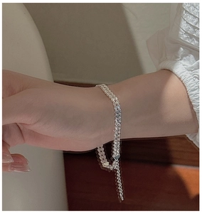 Close-up of minimalist S999 sterling silver laser-cut woven chain bracelet on wrist