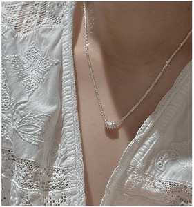 Detail of silver S925 necklace with multi-ring pendant worn on model with lace top