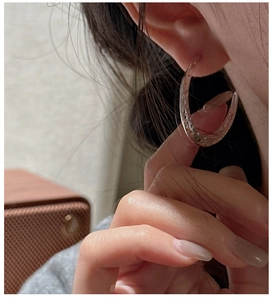 Detail view of silver S925 sterling silver hoop earring with hammered texture on model