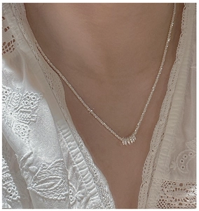 Detail of S925 sterling silver sparkling chain with tiny ring pendants on model neckline