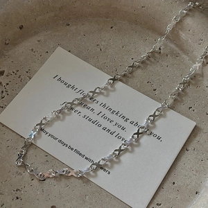 Minimalist S925 sterling silver X-link necklace displayed on a decorative stone tray