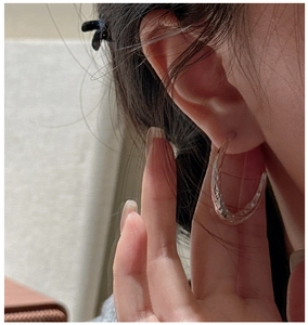 Close-up of textured S925 sterling silver hoop earrings with vintage hammered finish on model