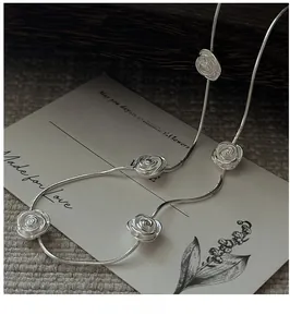 Detail of five 3D silver rose pendants on a fine snake chain necklace in vintage style