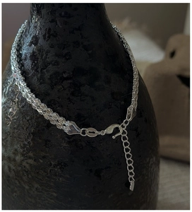 Close-up of multi-strand woven silver bracelet with adjustable lobster clasp and heart charm