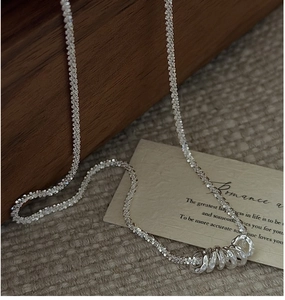 Detail of silver S925 necklace with hammered metal rings on a vintage wood background