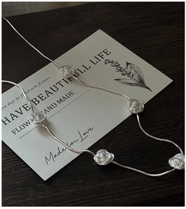 Detailed close-up of S925 silver rose necklace featuring five textured 3D floral motifs