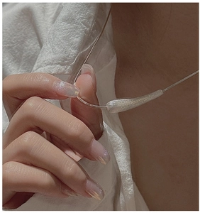 Close-up of minimalist S925 sterling silver necklace with textured curved bar pendant
