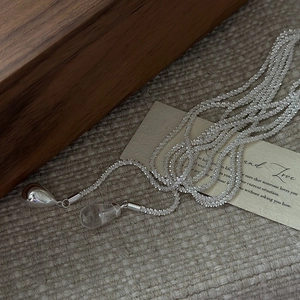 S925 sterling silver long necklace with teardrop crystal pendant on linen background