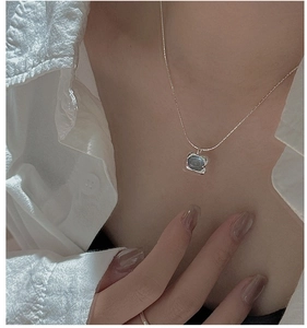 Macro shot of S925 silver necklace featuring a square blue gemstone on model