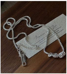 Close-up of S925 silver necklace with hammered rings and AG925 hallmark on wood