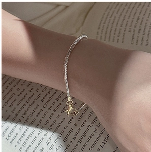 Close-up of a slim gold snake chain bracelet with a tiny star charm and lobster clasp