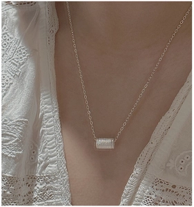 Dettaglio della collana in argento S925 con pendente cilindrico satinato su una modella