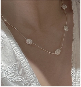 Close-up of S925 silver rose necklace on elegant white lace embroidery fabric