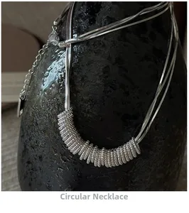 Detailed macro shot of a silver twisted circle pendant with a triple snake bone chain