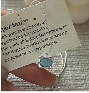 Macro shot of silver S925 necklace with oval light blue gemstone and irregular wavy edge