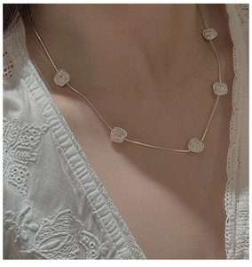 Detail of silver rose pendant necklace with floral relief charms on a fine snake chain
