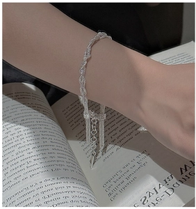 Detail of woven multi-layer silver bracelet with tassels on a French book background