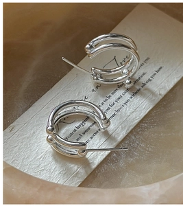 Detail shot of S925 sterling silver double-layer bead earrings on artistic prop paper