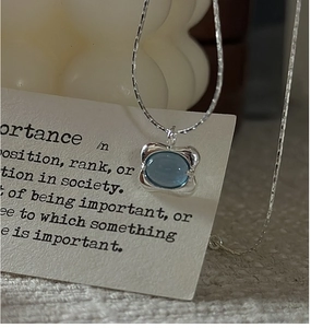 Close-up of S925 silver necklace featuring an oval sky blue gemstone with textured frame