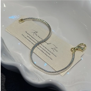 Close-up of S925 sterling silver snake chain bracelet with golden lobster clasp detail