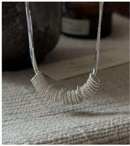 Macro shot of S925 sterling silver twist rings on a smooth snake chain necklace
