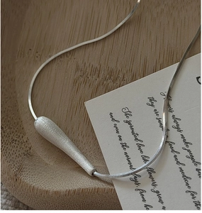 Macro view of brushed S925 sterling silver waterdrop pendant with sleek snake chain