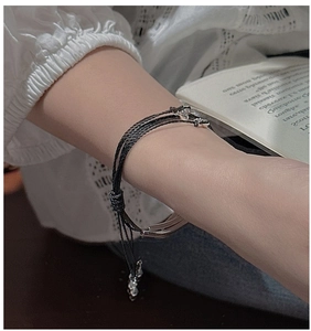 Detail of multi-strand black woven bracelet on wrist with elegant silver-tone metal clasp
