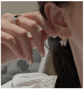 Detail of silver S925 cross and bead open ring with matching hoop earring on model