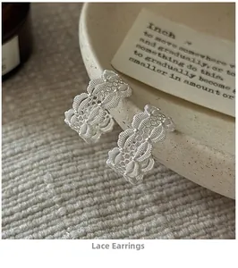 Gros plan de boucles d'oreilles en argent style dentelle sur un plateau beige