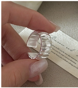 Macro detail of silver adjustable ring with vertical ripple texture and open band design