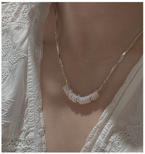 Macro detail of silver twist ring pendant on snake chain with elegant lace collar