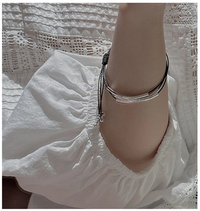 Detailed view of minimalist three-layer silver tube bracelet on model with lace sleeve