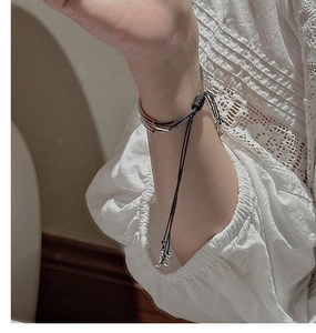 Detail of adjustable triple-layer braided black cord bracelet with silver beads on wrist