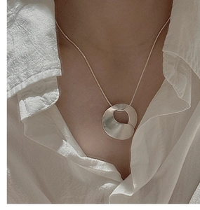 Minimalist matte S925 sterling silver disc pendant necklace on model with linen shirt
