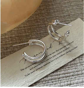 Macro detail of S925 sterling silver double-ring earrings on aesthetic display card