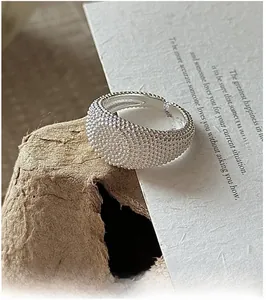 Macro shot of S925 sterling silver ring with beaded vintage texture on wooden background